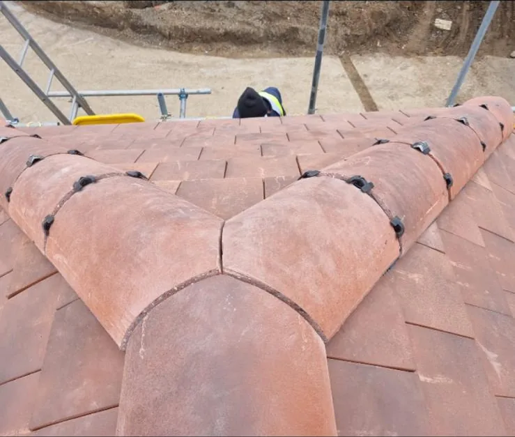 Traditional clay bonnet hip tiles on a plain tile roof